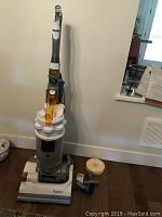 Full view of Dyson upright vacuum cleaner with yellow transparent handle and base, accompanied by hose and filter.