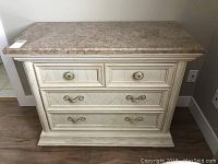 Front view of Thomasville dresser showing granite top, 3 drawers with brass and round knob handles.