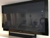Front view of widescreen plasma television on stand showing black bezel