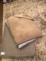 Canvas dog bed in taupe color labeled L.L.Bean, rectangular shape, placed on carpeted floor.
