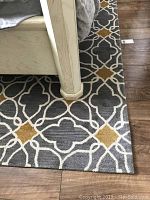 Partial shot under bed showing rug pattern and placement