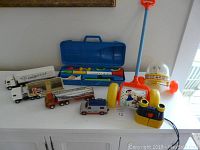 Photo of the full toy lot showing multiple diecast trucks, Fisher Price musical push toys and recorder set, and binoculars.
