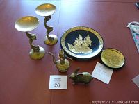 Photo of entire lot showing two gold leaf lacquer plates, two brass candlesticks, brass rabbit figurine, and brass jug.