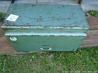 Closed metal toolbox showing exterior surface with paint chipping and rust.