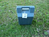 Closed blue hard plastic carrying case on grass.