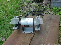 Front view of Ashland Model 1780 bench grinder showing cylindrical motor housing and attached safety shields over the grinding wheels.