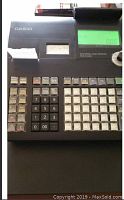 Top front view of Casio cash register keyboard including numeric keypad, function keys and built-in printer with paper roll.