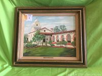 Full view of the framed oil painting depicting a mission with a green background and gold frame.