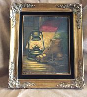 Frontal view of the framed oil painting showing the lantern and boot still life with decorative frame.