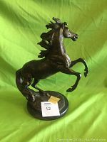 Bronze horse statue on marble base, side view showing the horse rearing.