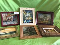 Full view of six assorted oil paintings in various frames against green background