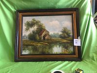 Full view of the framed oil painting showing the entire artwork and frame against a green background.