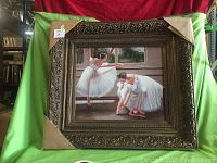 Frontal view of the large oil painting of ballerinas with ornate frame, partially protected by cardboard corner covers.