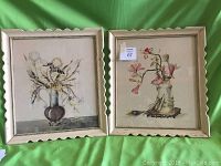 Pair of framed still life floral paintings on green background, front view showing overall condition and framing