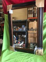Full frontal image of beveled mirror standing upright against a green backdrop, showing the large dark wooden frame and clear beveled glass mirror.