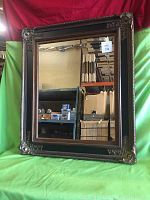 Front view of the large beveled mirror in a dark wood ornate gallery frame with gold corner accents.