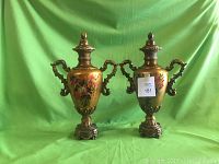Pair of hand painted floral urns shown against green background