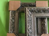 Pair of pewter-colored wood gallery frames with detailed floral and scroll carving, showing front side with cardboard corner covers.