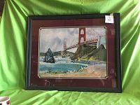 Front view of framed watercolor painting depicting the Golden Gate Bridge with natural landscape and ocean water, inside a dark wooden frame and maroon mat.