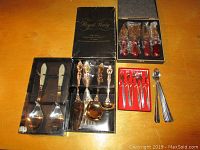 Overall view of grouped utensil sets including boxed cheese knives, salad serving set, and small forks and spoons.