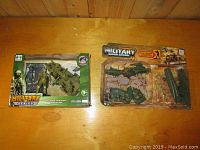 Two military toy sets packaged in original boxes on wood surface.