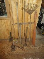 Wide view of entire lot showing various garden tools and wooden post arranged against wooden wall