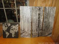 Four canvas prints displayed; three long rectangular birch trees prints and one smaller square world map print.