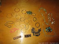Photo showing an assortment of 22 bracelets including metal bangles, beaded bracelets, elastic and decorative designs laid out on a wooden surface.
