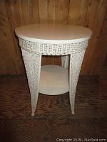 Front view showing the entire round table with wicker legs and lower shelf.