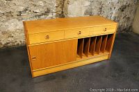 Front view of record cabinet showing three drawers, sliding door and record slots