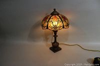 Lamp turned on showing front view of stained glass shade and base