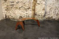 Front view showing kidney-shaped glass top and walnut base