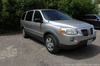 Front and driver side view of silver minivan parked outdoors