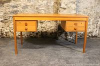 Straight-on front view showing four drawers with square teak pulls and tapered legs