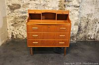 Frontal view of teak desk showing small top drawers, cubbies, and three lower drawers