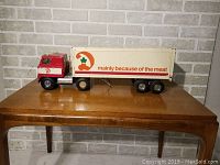 Side view of the vintage Dominion truck and trailer in red, white, and cream with 'Mainly Because of the Meat' slogan on the trailer side.