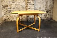 Front view of dining table showing arched legs and cross stretcher