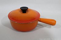 Full view of vintage orange Le Creuset single handle pan with lid, showing condition and color.