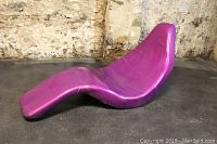 Front left view of purple fish-shaped lounge chair against stone wall