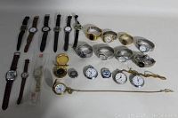 Full lot view showing a mix of wristwatches, pocket watches, and chains arranged on surface