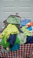Pile of assorted women's plus size clothing items on a red and white checkered table.