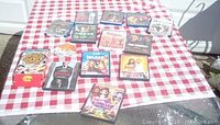 Lot of 14 DVDs displayed on a red and white checkered cloth, showing cases and one loose disc in front.