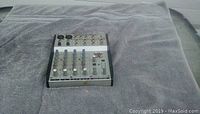 Photo showing the Behringer Eurorack MX 302A mixing console on a gray fabric surface.