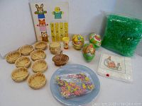 Photo showing full lot with 9 flat round baskets, one handle basket, 3 paper eggs, blue plates, bunny napkins, printed character sheet, green grass bag, and confetti bag on plate.