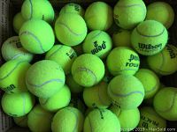 Photo showing a large quantity of used, dead tennis balls in mixed brands including Wilson, Penn, Dunlop, and green dot beginner balls.