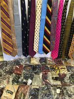 Photo showing a variety of neckties hanging and individually bagged ties underneath. Ties have various patterns including stripes, dots, and paisley in many colors.