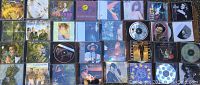 Photo of assorted music CDs laid out flat showing front cover art with various artists and genres in jewel cases