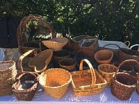 Various assorted baskets of different shapes and sizes arranged on a table outdoors, showing details of weave and handles.
