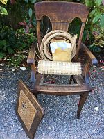 Wooden armchair with broken seat, showing missing center and caning supplies on the chair