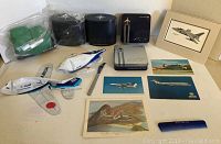 Overview of airline memorabilia lot with model airplanes, postcards, amenity kits, comb, menu, and art piece